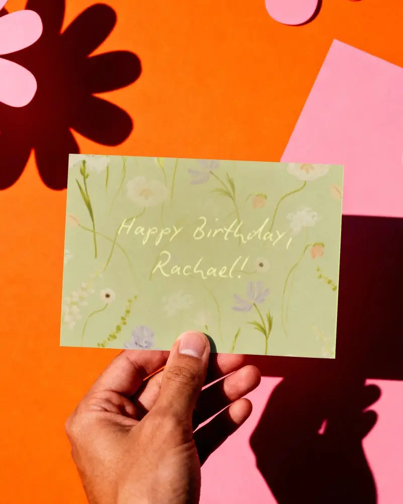Greeting Card Mockup In Hand Against Abstract Floral Shadow Background For Presentation