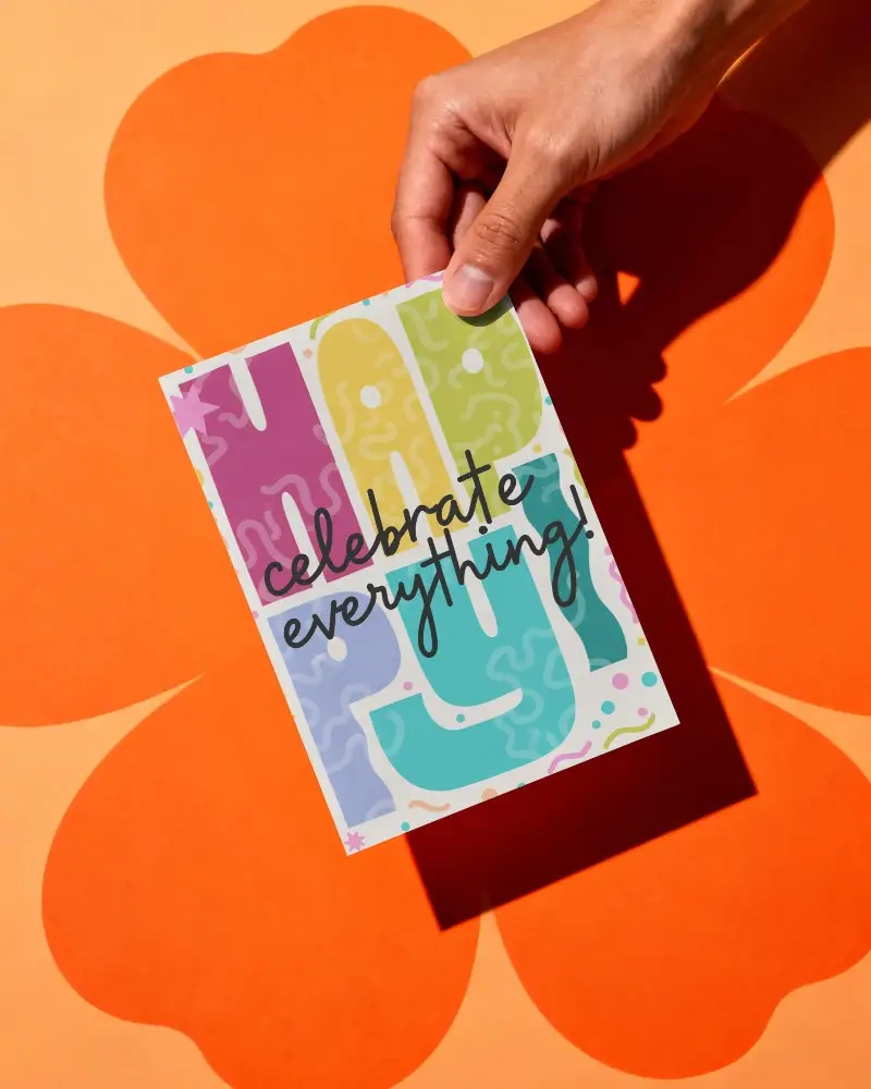 Greeting Card Mockup Showcased By Hand With Bold Flower Shape Background