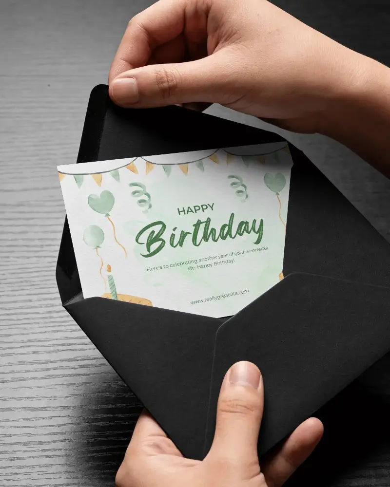 Close Up Of Hands Holding Black Envelope With Card Mockup On Dark Wooden Desk