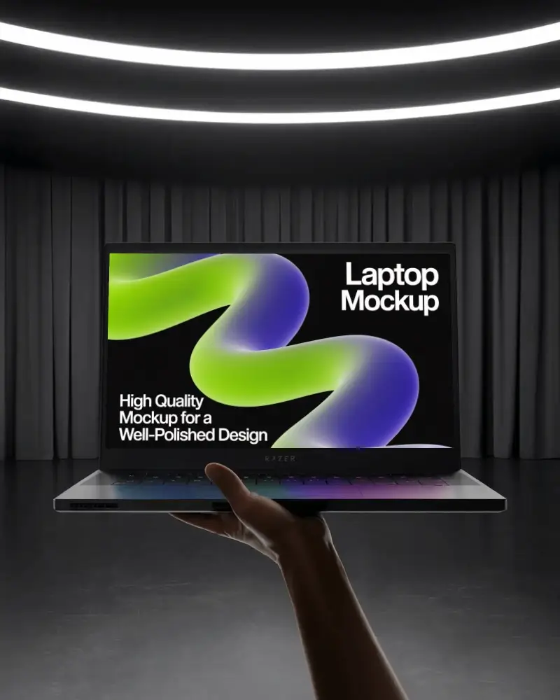 Razer Gaming Laptop Mockup Held In Hand Under Spotlight With Dark Curtains And Modern Stage