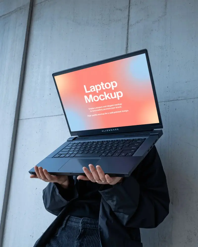 Alienware Gaming Laptop Mockup Held Up By Person In Modern Minimal Setting With Concrete Wall