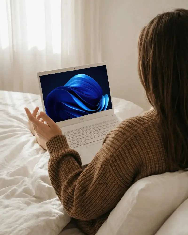 Woman Using Accer Laptop In Bed Working Remotely Or Studying In Comfortable Home Environment