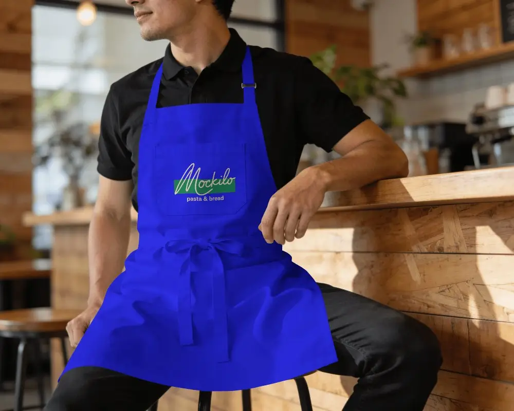 Cafe Interior Barista Style Apron Mockup On Male Model Sitting At Counter Warm Cafe Light