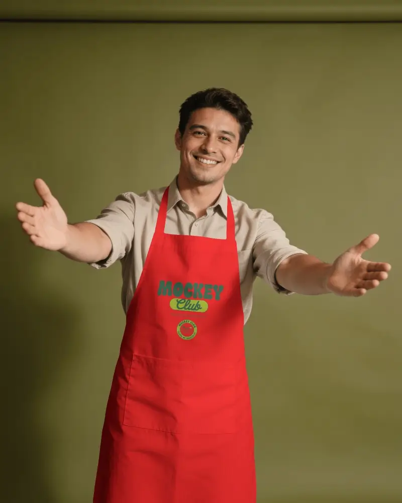 Smiling Male Model Apron Mockup With Open Arms On Olive Green Studio Background