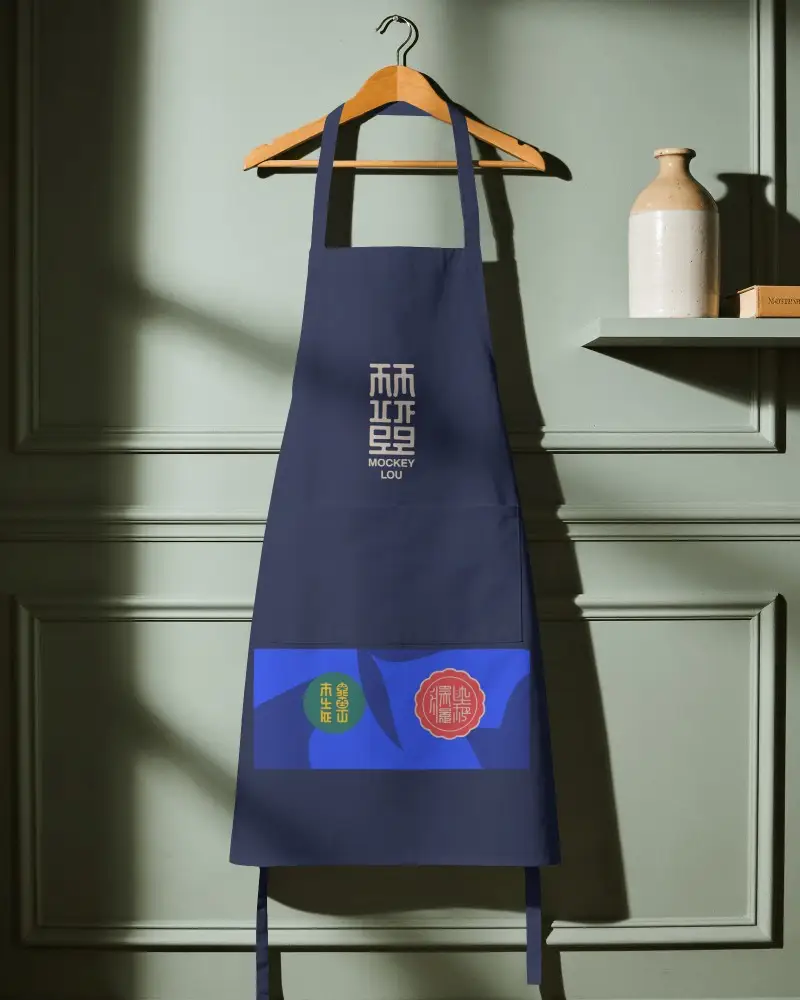 Barber Apron Mockup Hanging On Wooden Hanger Against Muted Green Wall With Hard Sunlight