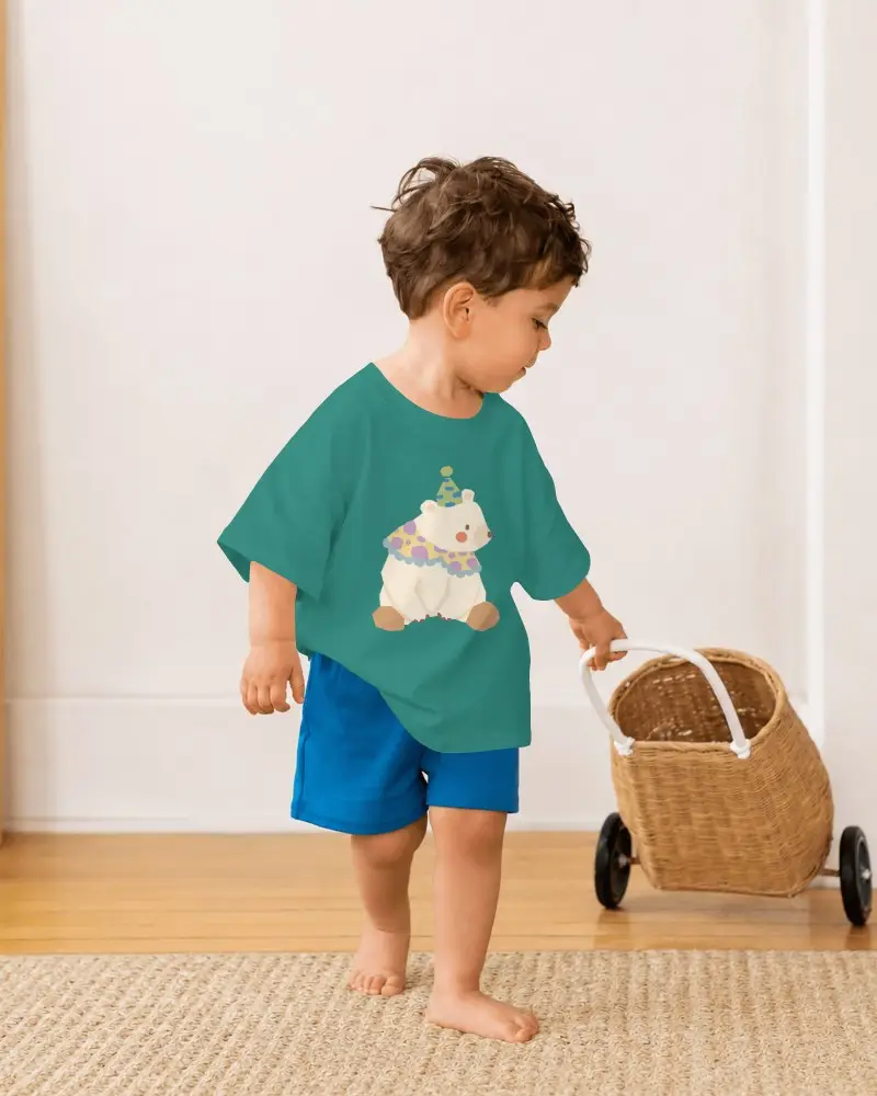 Baby Tee Mockup Toddler Boy Standing Side View In Bright Home Interior With Wicker Toy Cart