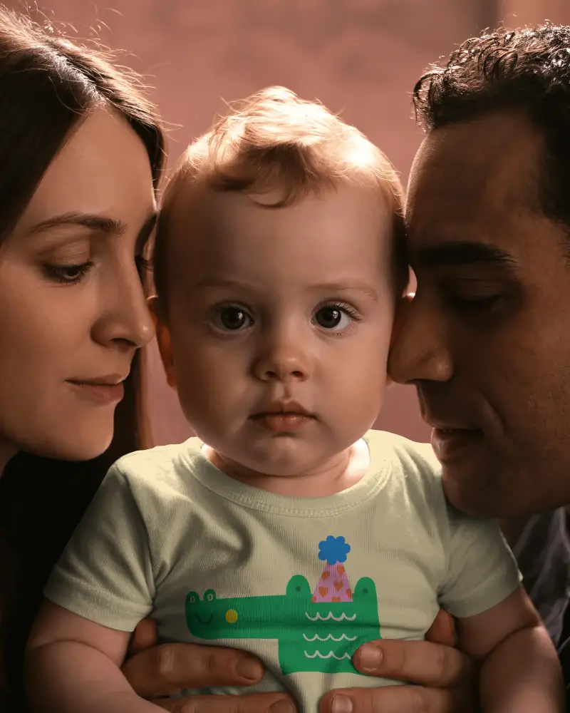 Family Portrait Baby Tee Mockup Baby Held Between Parents Closeup Emotional Lifestyle Scene