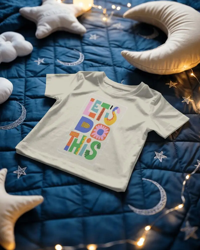 Baby Tee Mockup Infant Tshirt Flat Lay On Star Quilt With Moon Pillows And Warm Fairy Lights