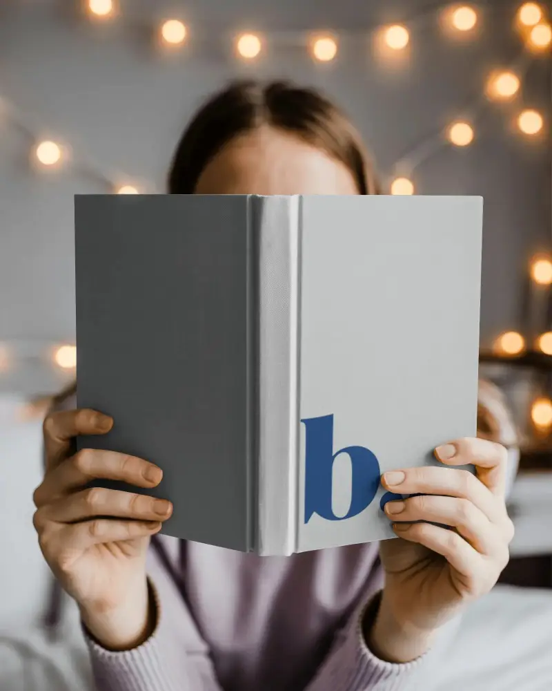 Woman Reading Hardcover Book Mockup Cozy Indoor Setting Fairy Lights Background