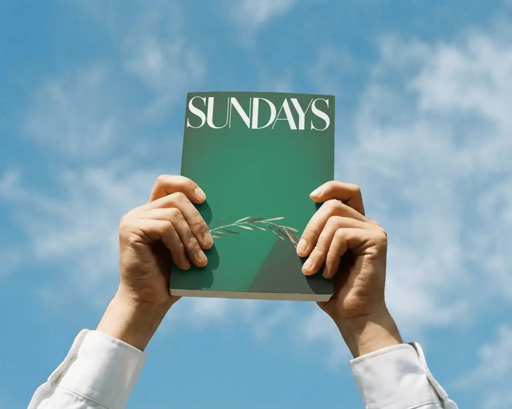 Person Raising Closed Book Mockup Upward Under Bright Sky Perfect For Cover Display