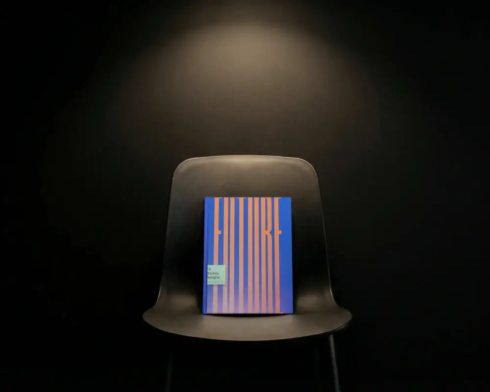 Hardcover Book Mockup On Minimalist Chair With Dark Background And Spotlight Illumination