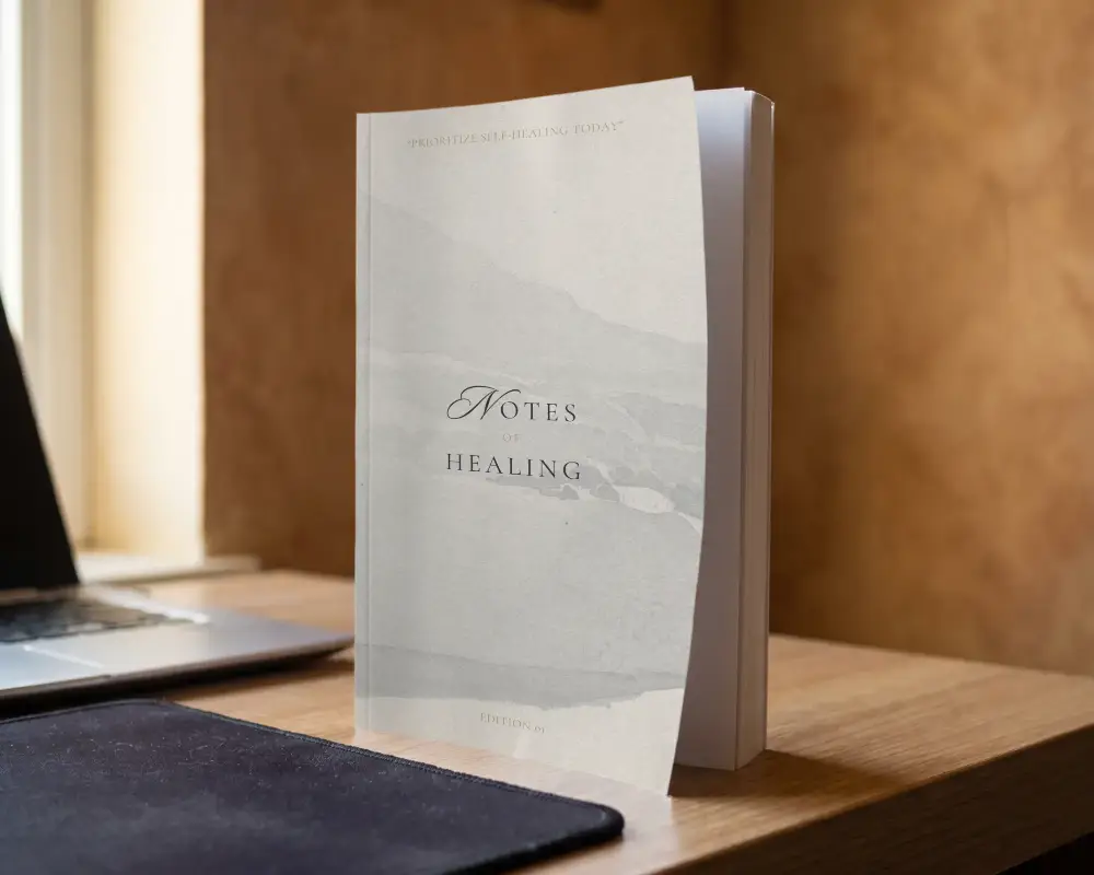 Blank Book Mockup Standing On Wooden Desk With Laptop For Design Presentation