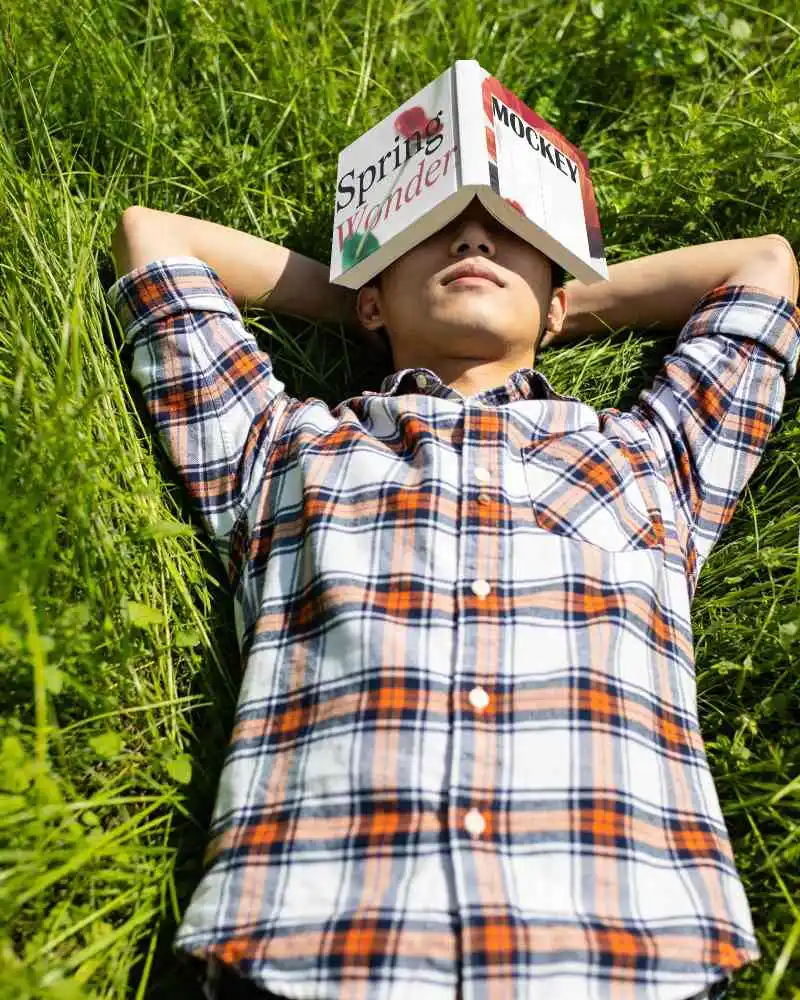 Person Relaxing In Nature With Book Mockup On Face Outdoor Relaxation And Leisure Time