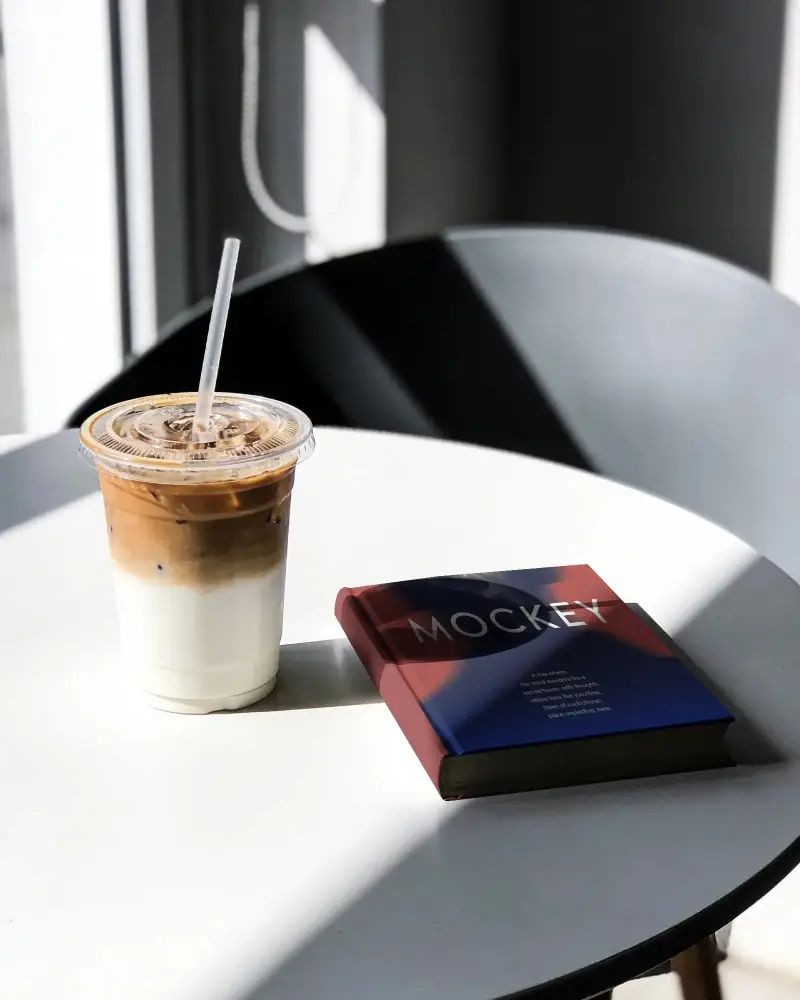 Sleek Modern Book Mockup With Cold Beverage On Minimalist Round Table Perfect For Design Display