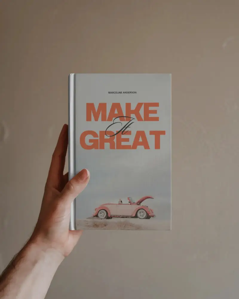 Blank Hardcover Book Mockup Held Upright Against Muted Brown Wall Closeup Of Hand And Simple Setting