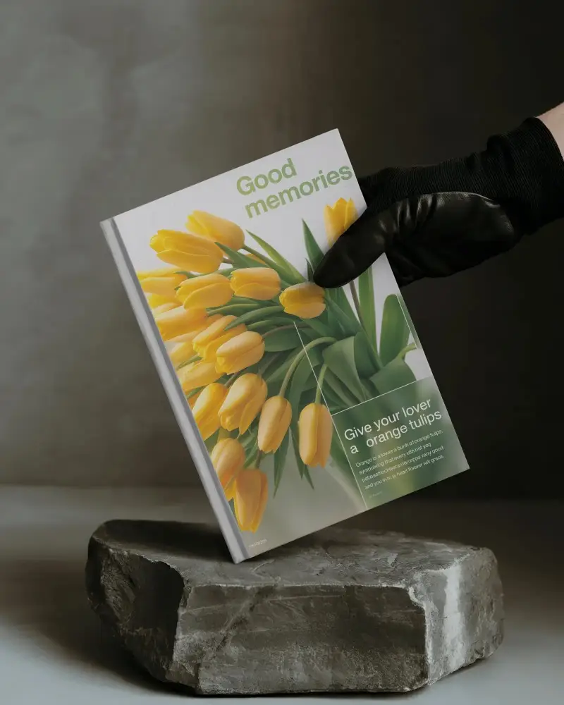 Angled A4 Book Mockup Held By Gloved Hand Above Stone Pedestal In Moody Lighting With Dark Minimal Background