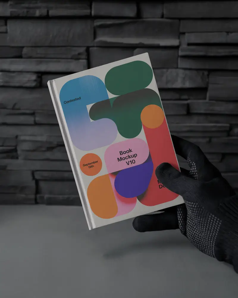 Black Gloved Hand Holding Book Mockup In Front Of Dark Textured Slate Wall