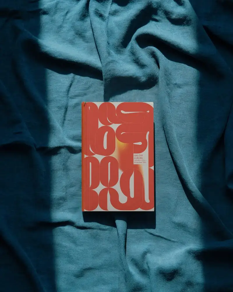 Top View Book Mockup On Teal Fabric Surface With Strong Contrasting Sunlight Shadow