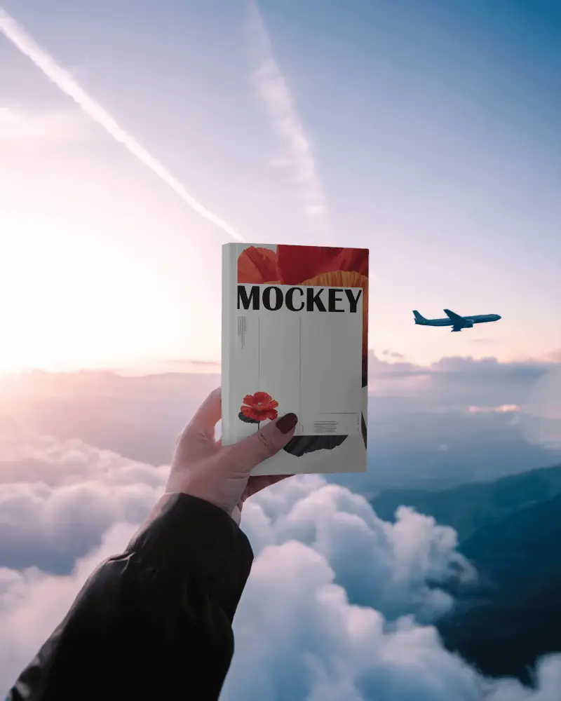 Hand Holding Blank Book Mockup Against Sky And Airplane Background For Design Display