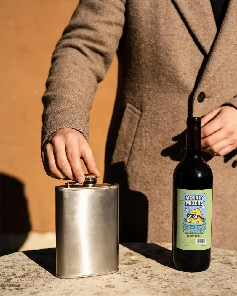 Sleek Metal Flask And Glass Wine Bottle With Blank Label On Rustic Stone Table