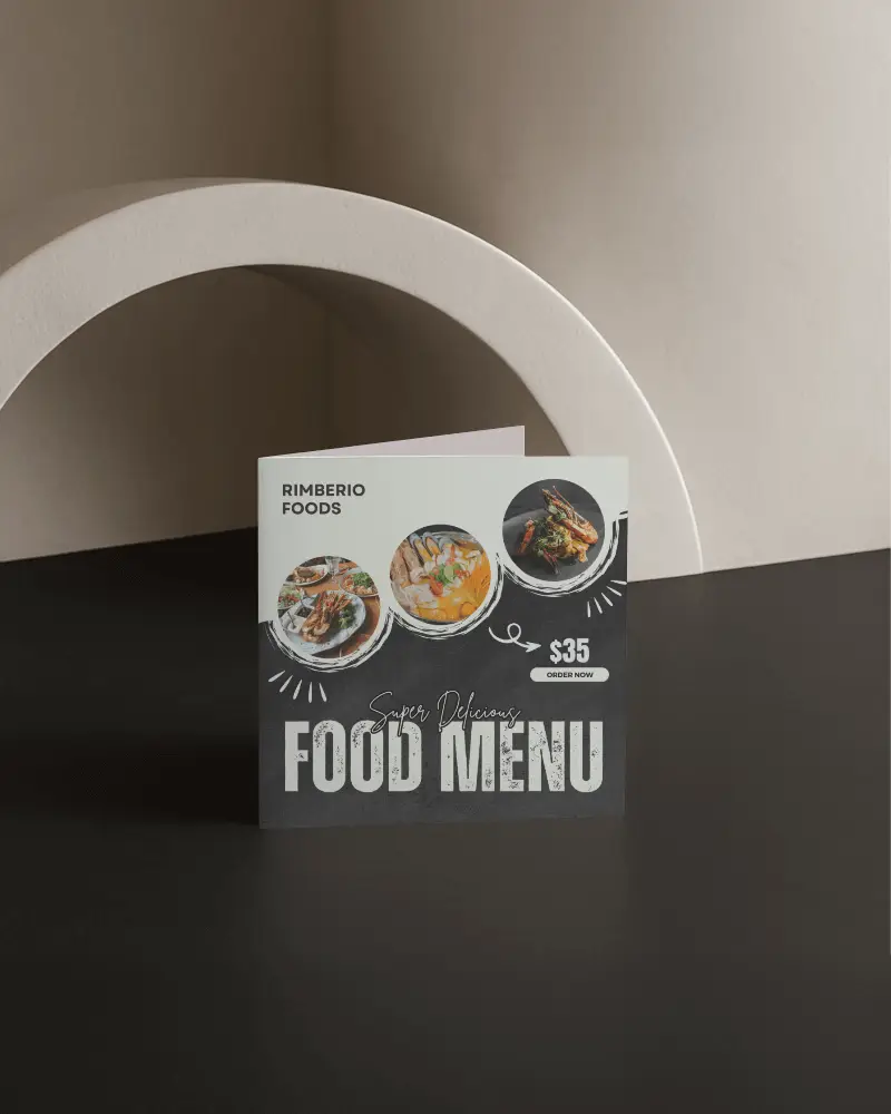 Square Folded Brochure Mockup Standing On Black Surface Against Textured Arch Backdrop Soft Neutral Lighting Modern Minimal Promotional Display Scene