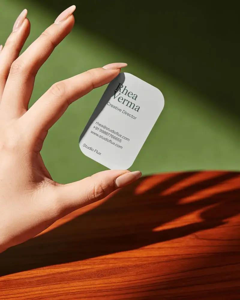 Hand Holding Minimalist Rounded Business Card Mockup On Wooden Table Background