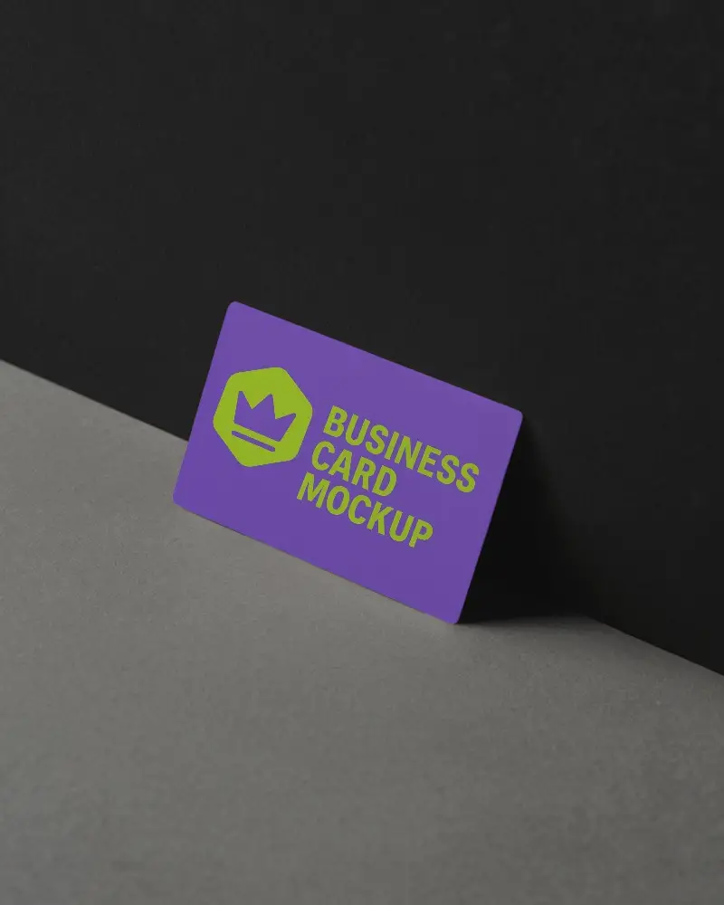 Tilted Dark Toned Business Card Mockup Against Black Wall And Grey Floor With Soft Diffused Light