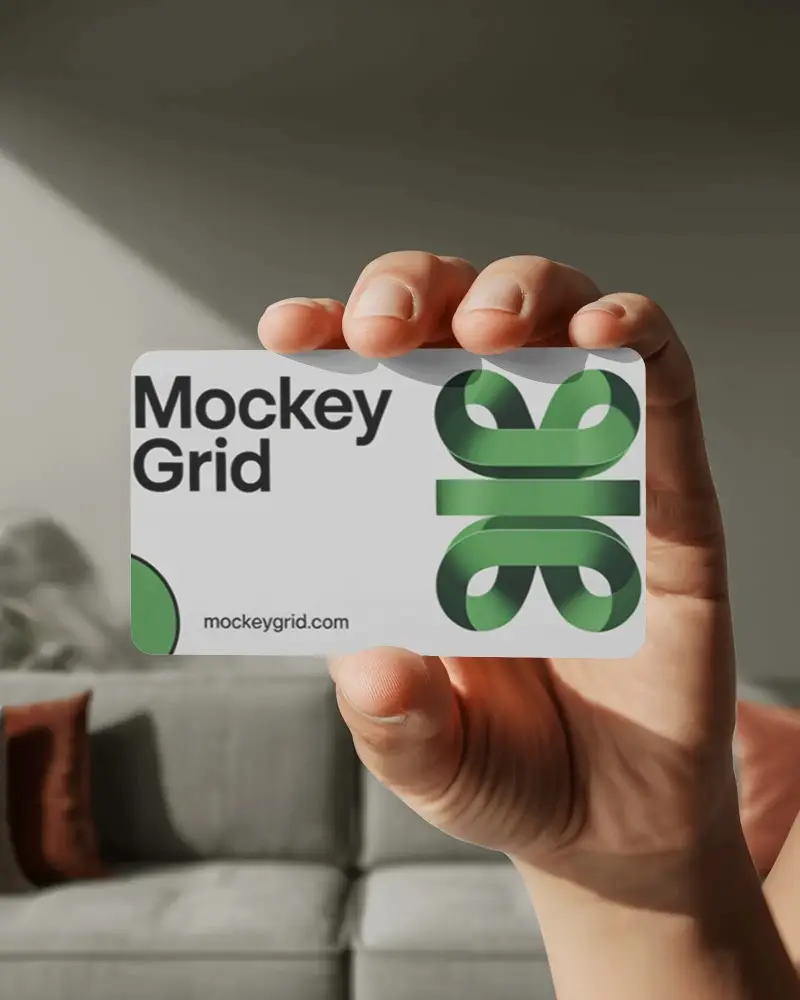 hand-holding-horizontal-business-card-mockup-floating-over-sofa-background-in-natural-light