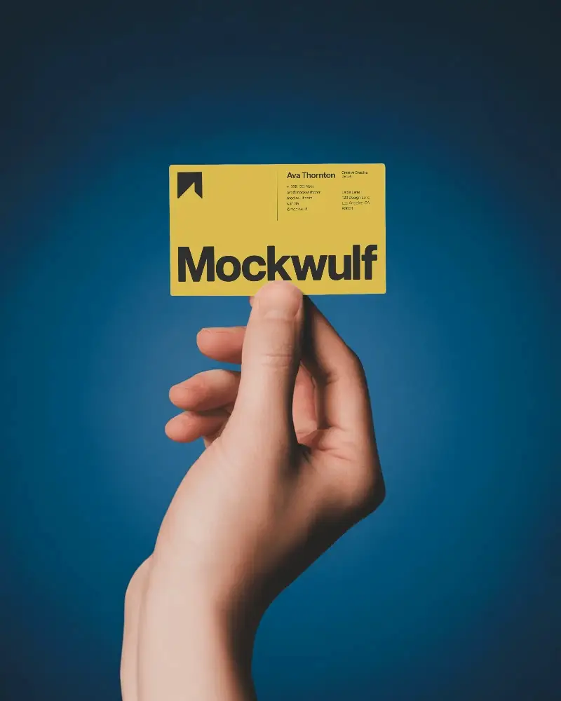 Hand Holding Blank Business Card Mockup Against Solid Background For Design Presentation