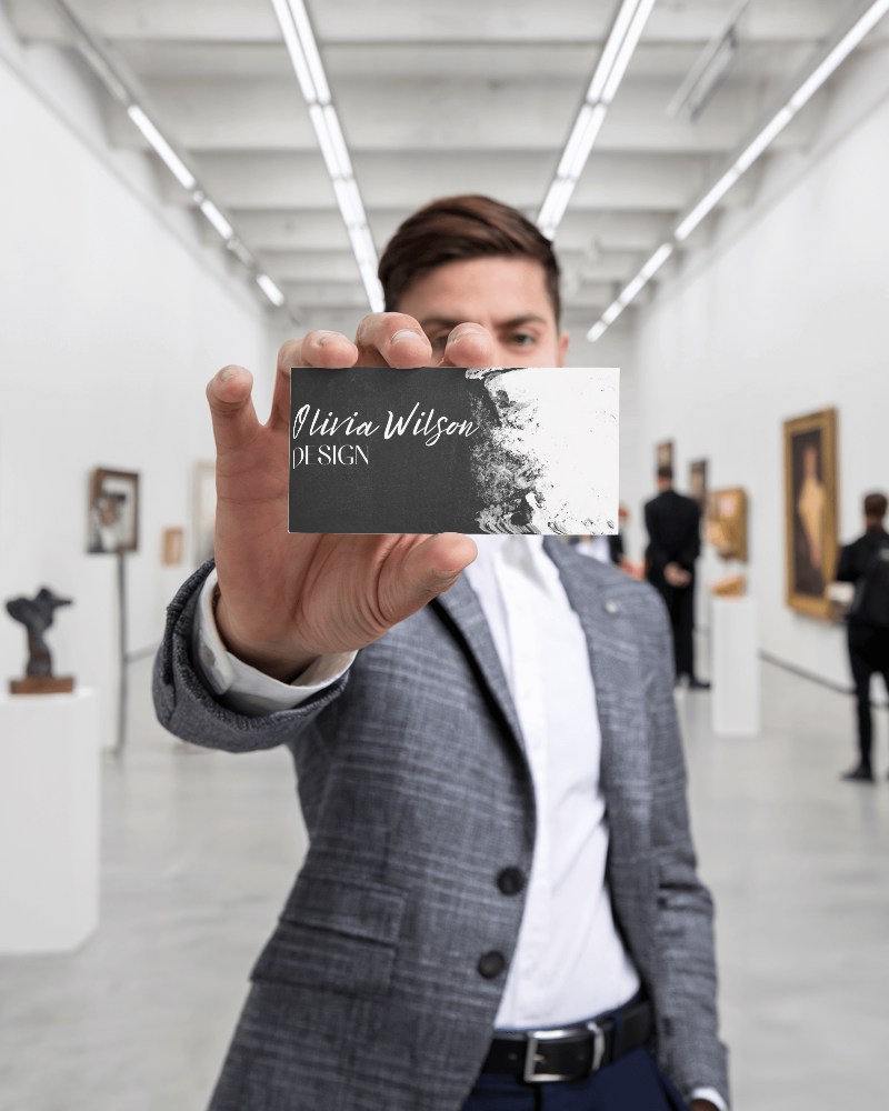 Art Gallery Business Card Mockup Man Holding Card In Sleek Exhibit Space Modern Aesthetic