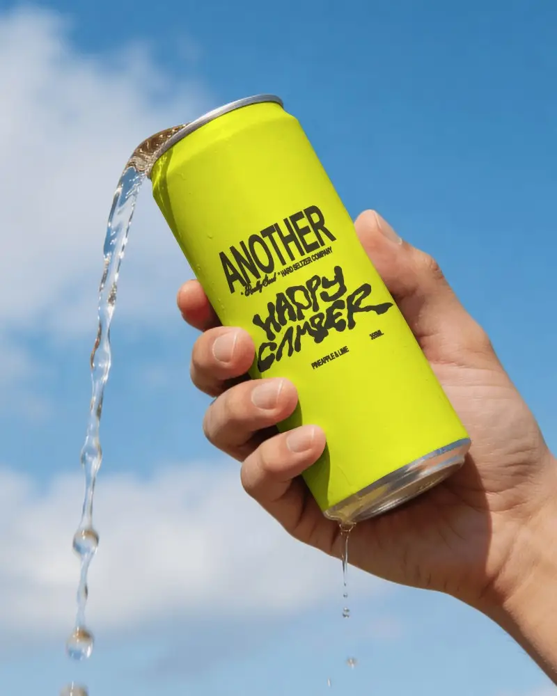 Pouring Beer Can Mockup Held Against Blue Sky With Fresh Liquid Stream And Summer Outdoor Light