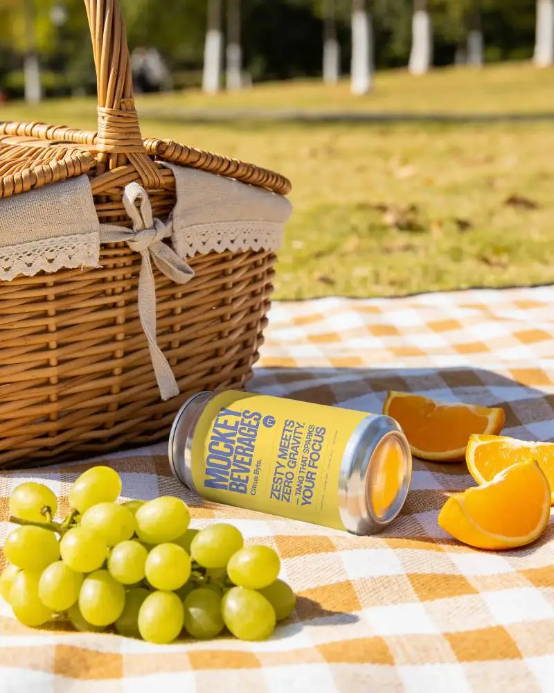 Realistic Craft Beverage Can Mockup Set On Picnic Blanket With Orange Slices And Grapes