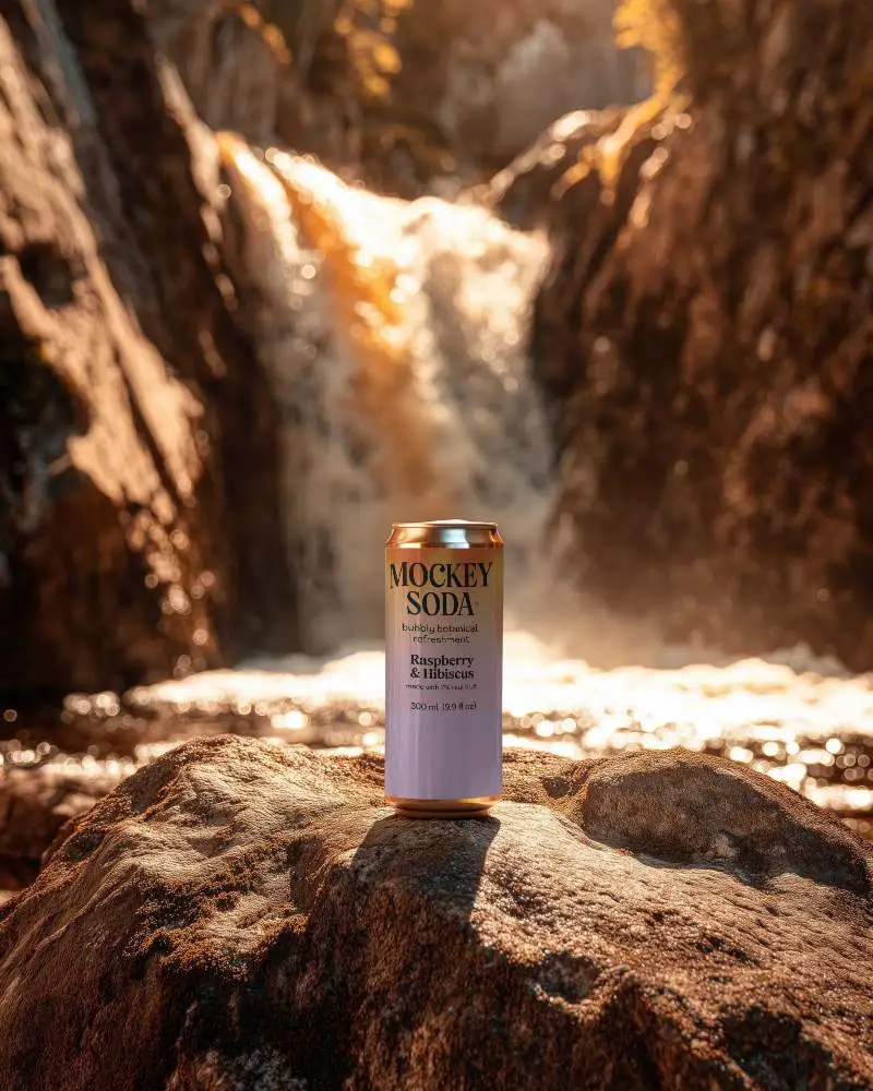 Premium Beverage Can Mockup Placed On Rock Outdoor Setting With Waterfall In Background