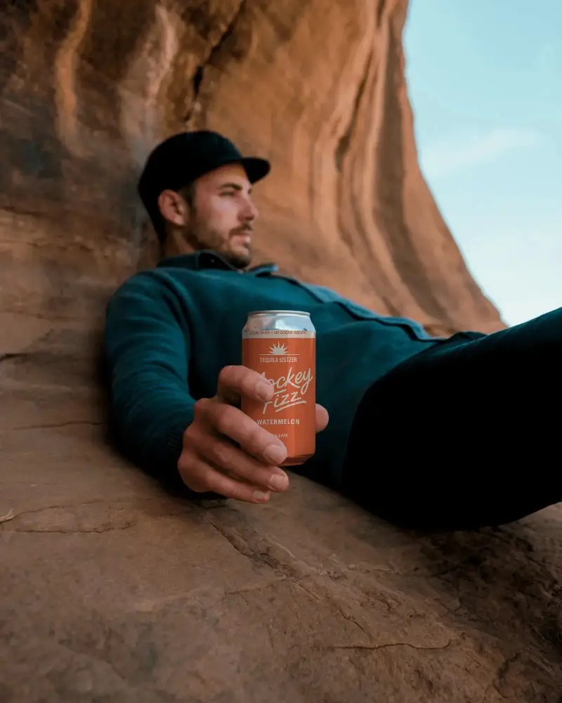 Nature Adventure Beverage Can Mockup Man Resting On Rocks Holding Drink Container