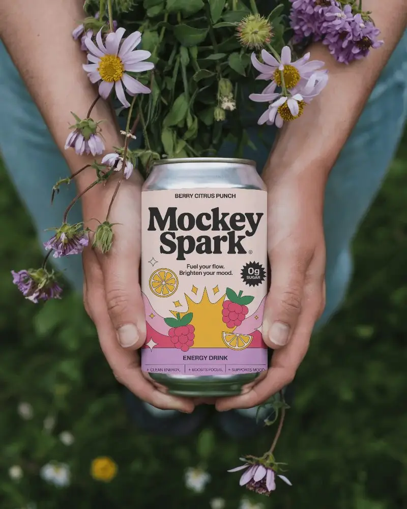 Person Holding Blank Can Mockup Surrounded By Nature Flowers And Greenery For Design