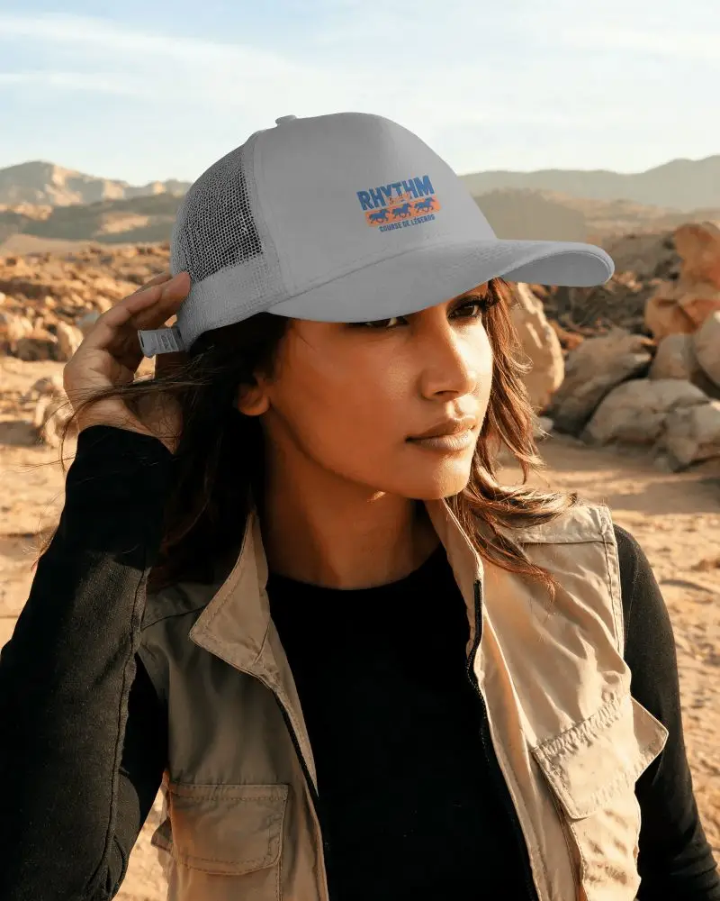 Female Model Wearing Trucker Cap Adjusting Back Strap On Desert Background With Soft Natural Light