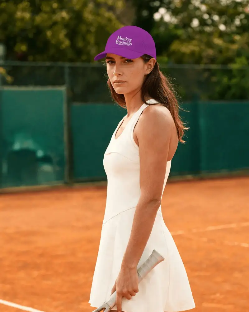 Female Tennis Player Wearing Tennis Cap Holding Racket And Looking Confident On Court