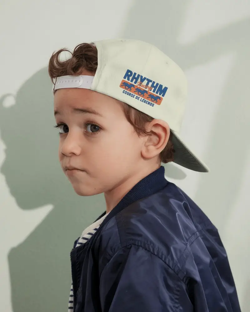 Backward Kid Cap Mockup Against Mint Wall Showing Shadow And Casual Expression With Neutral Outfit
