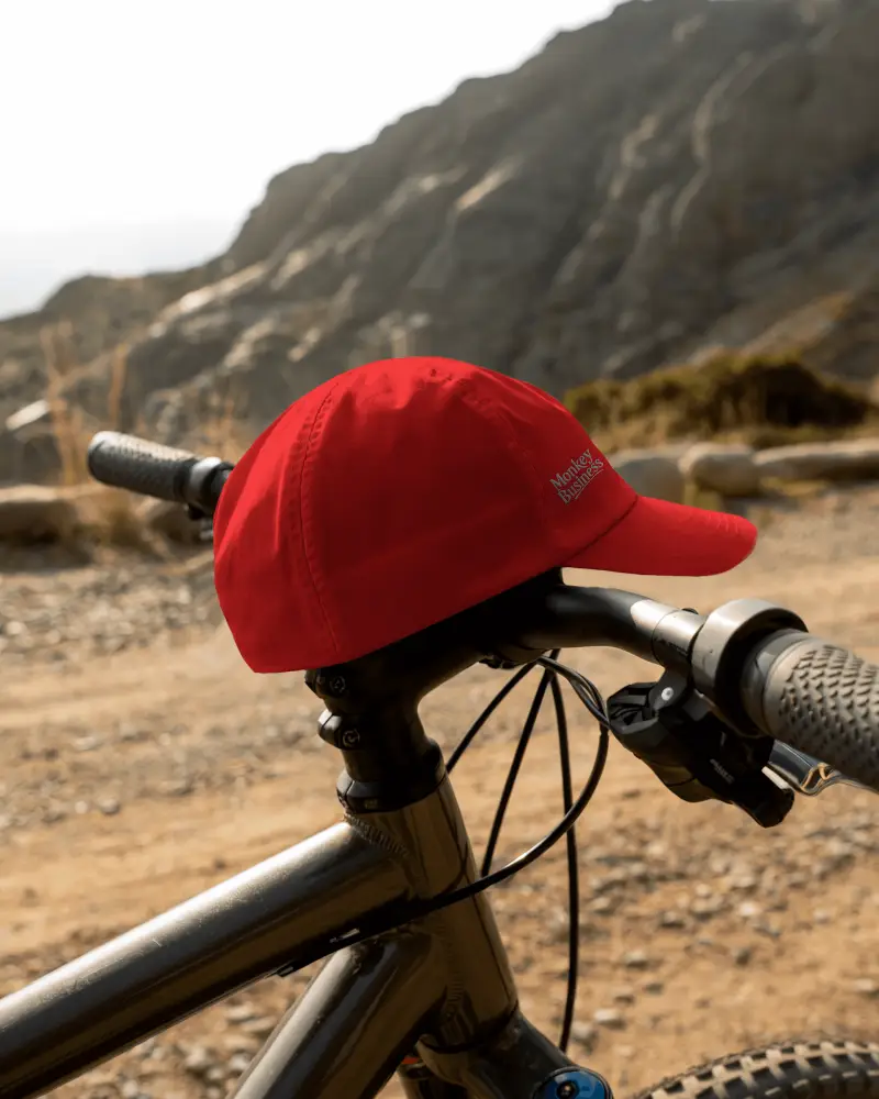 Outdoor Trail Cycling Cap Mockup Resting On Bike Handlebar With Rocky Mountain Scenic Backdrop