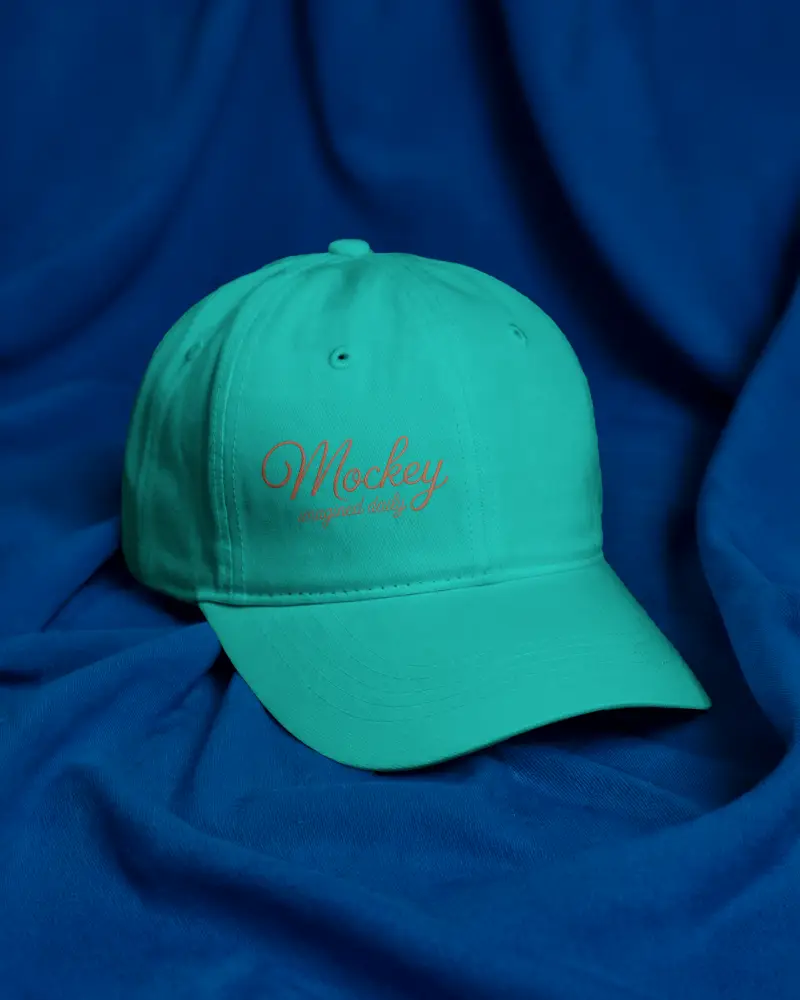 Fabric Surface Cap Mockup Classic Baseball Hat Resting On Blue Cloth Backdrop Studio Shot