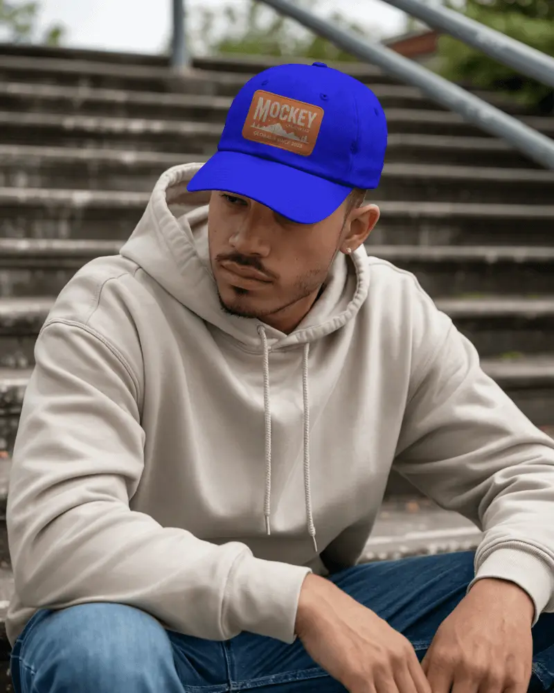 Urban Lifestyle Cap Mockup On Male Model Wearing Hoodie Sitting Outdoor Streetwear Vibes