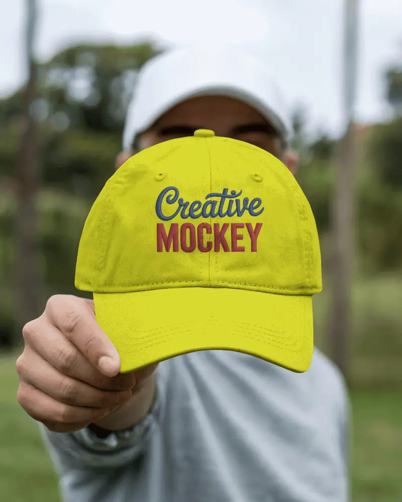 Outdoor Cap Mockup Hand Holding Forward In Focus Green Nature Background Lifestyle Streetwear