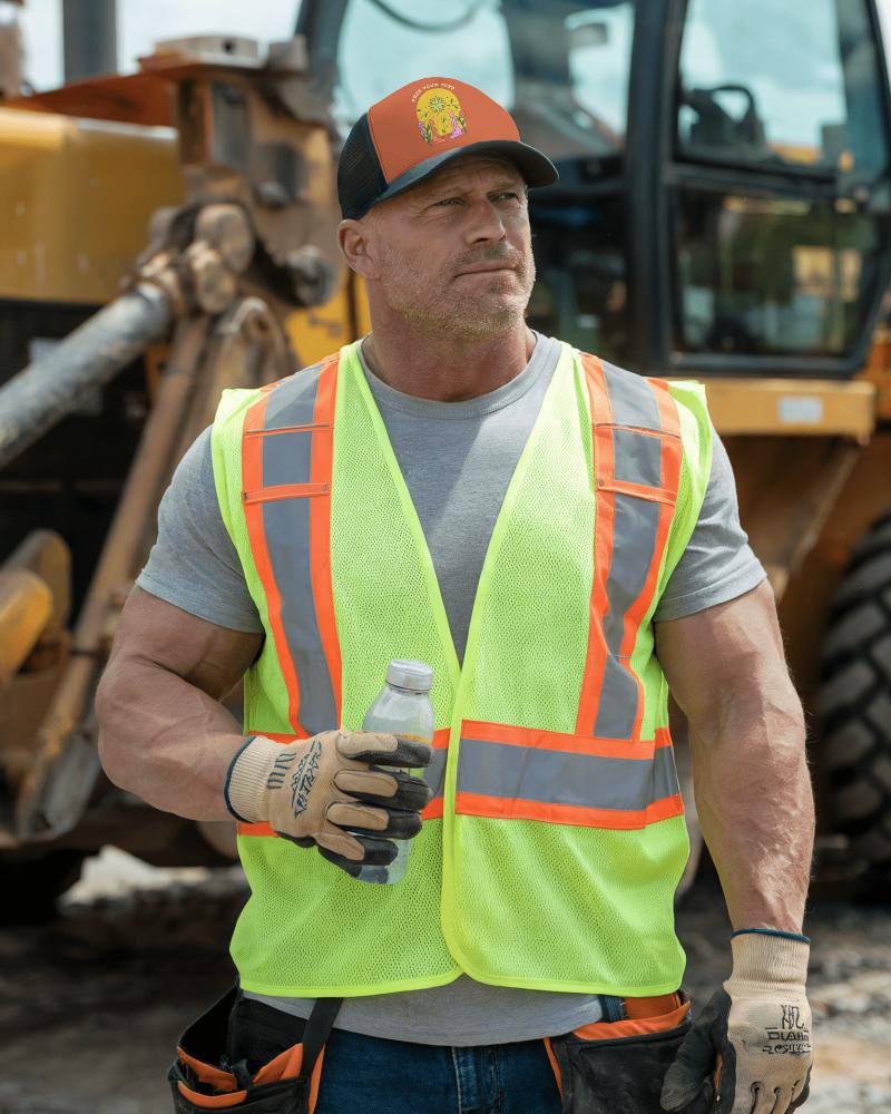 Construction Site Trucker Hat Mockup Rugged Builder In Hi Vis Safety Wear Standing Next To Heavy Machinery