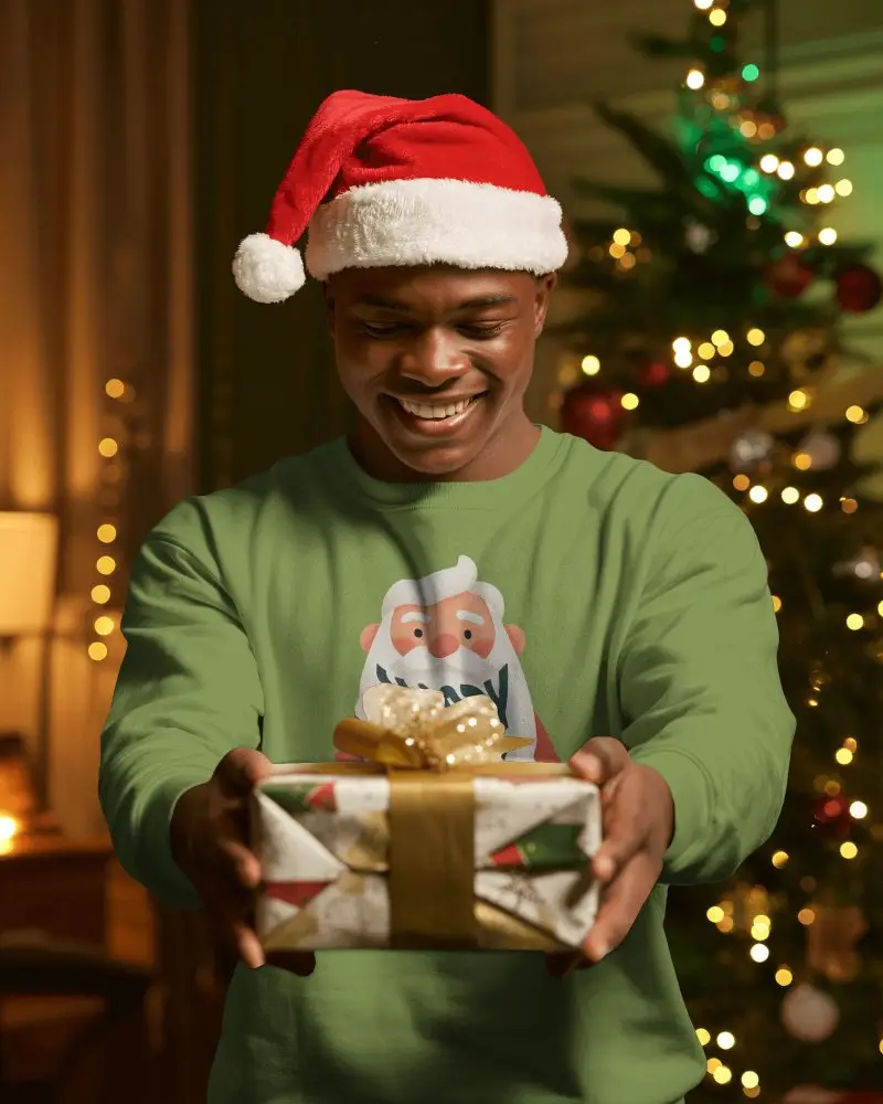Christmas Sweatshirt Mockup Man In Santa Hat Holding Gift With Warm Tree Lights