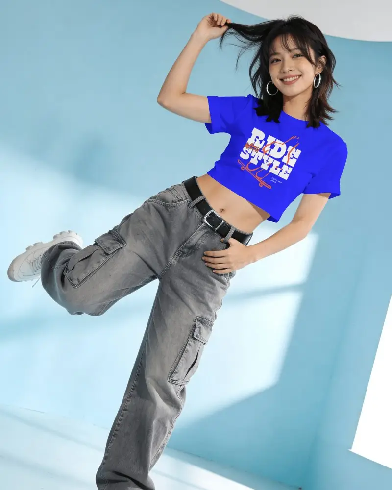 Short Sleeve Crop Top Mockup Female Model Leaning Sideways In Blue Studio With Playful Hair Pose