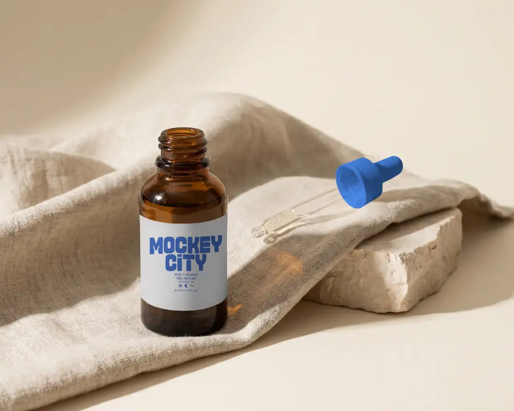 Cosmetic Dropper Bottle Mockup Displaying Label On Textured Cloth With Detached Dropper Lid