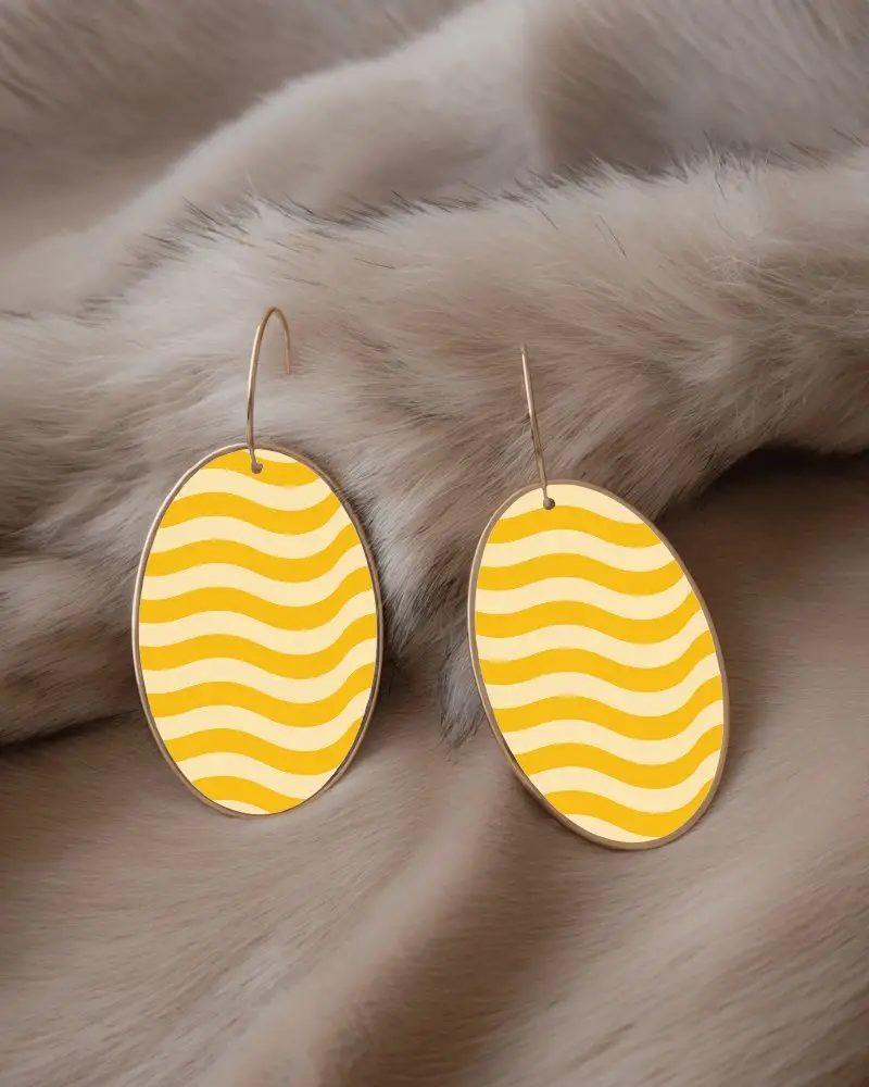 Sleek Golden Hoop Earrings With Black Oval Pendants Resting On Soft Faux Fur Background