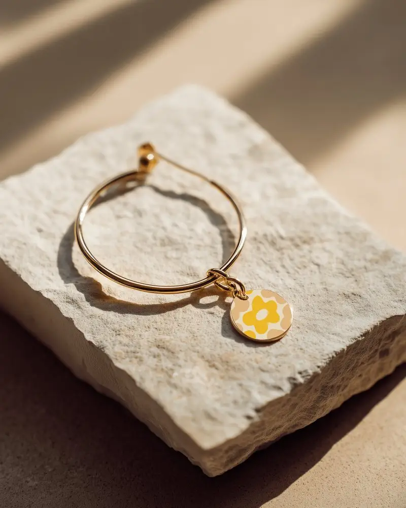 Gold Hoop Earring With Black Circle Charm On Stone Surface With Soft Natural Lighting