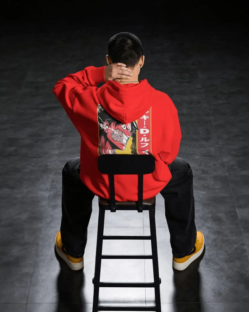 Hoodie Mockup Back View Male Model Sitting On Chair With Hand Behind Neck In Dark Studio