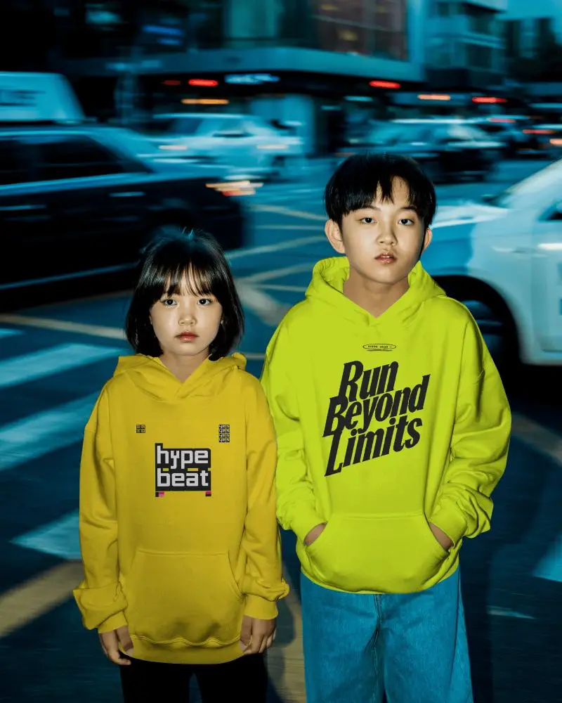 Urban Night Hoodie Mockup Featuring Two Kids Standing On Busy City Crosswalk